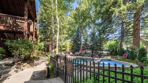 A wooden cabin with a pool surrounded by trees.