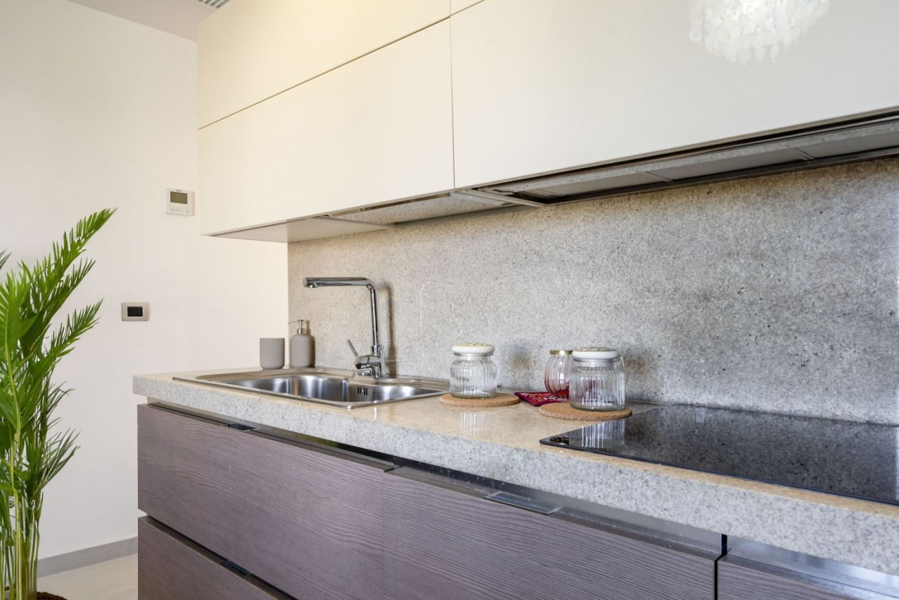 A modern kitchen with granite countertops, stainless steel sink, and a built-in range hood.