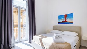 A hotel room with a bed, a painting, and a view through a window. - Maison Emanuele Double Apartment (Naples)