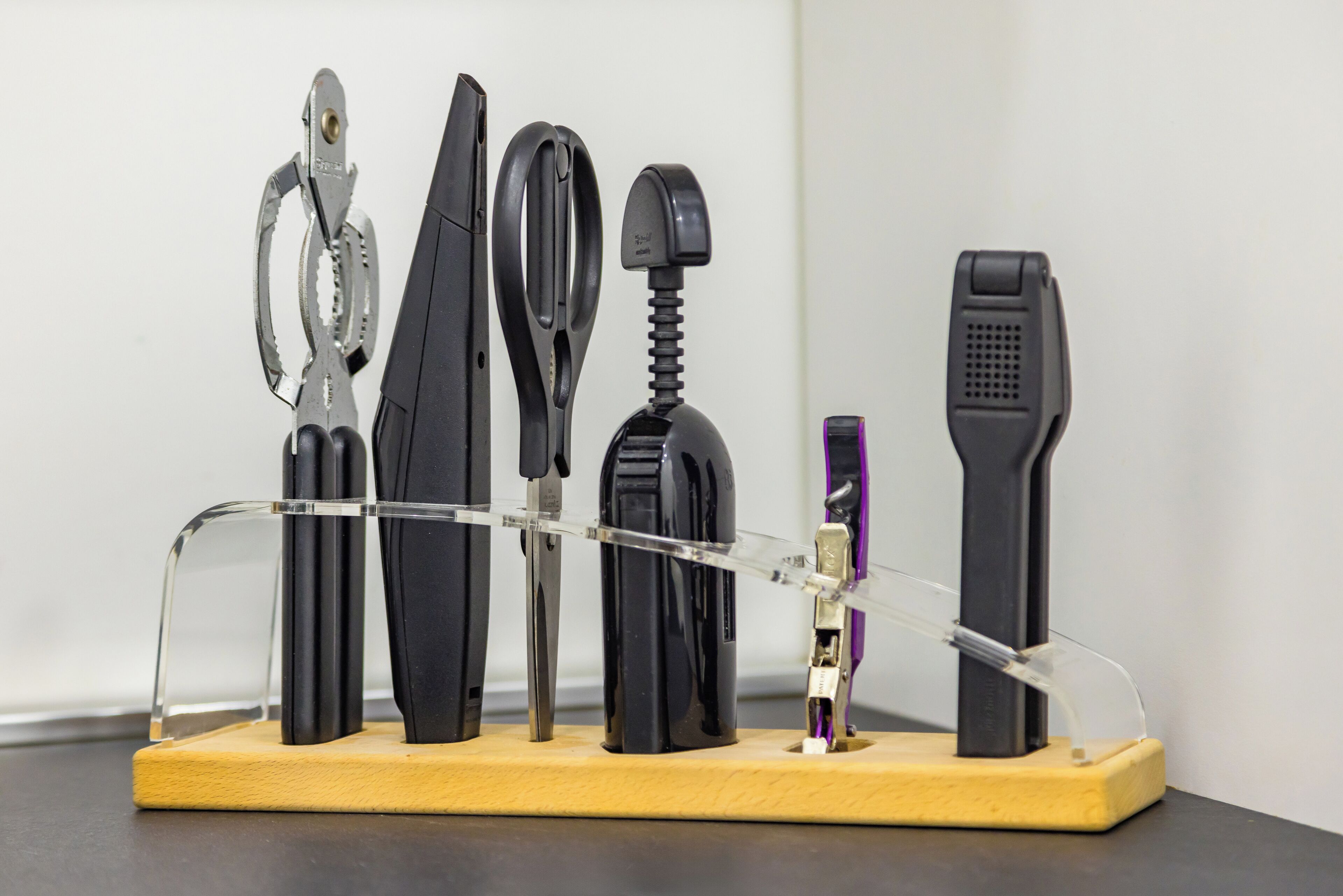 A collection of tools mounted on a wooden stand against a plain background.