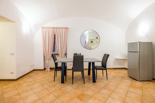 A dining area with a table, chairs, a mirror, and a refrigerator. - Materdei Beautiful Terrace by Napoliapartments (Naples)