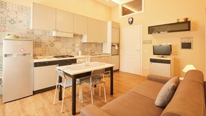 A compact kitchen with a dining area, a sofa, and a TV. - Napoli Fuori (Naples)