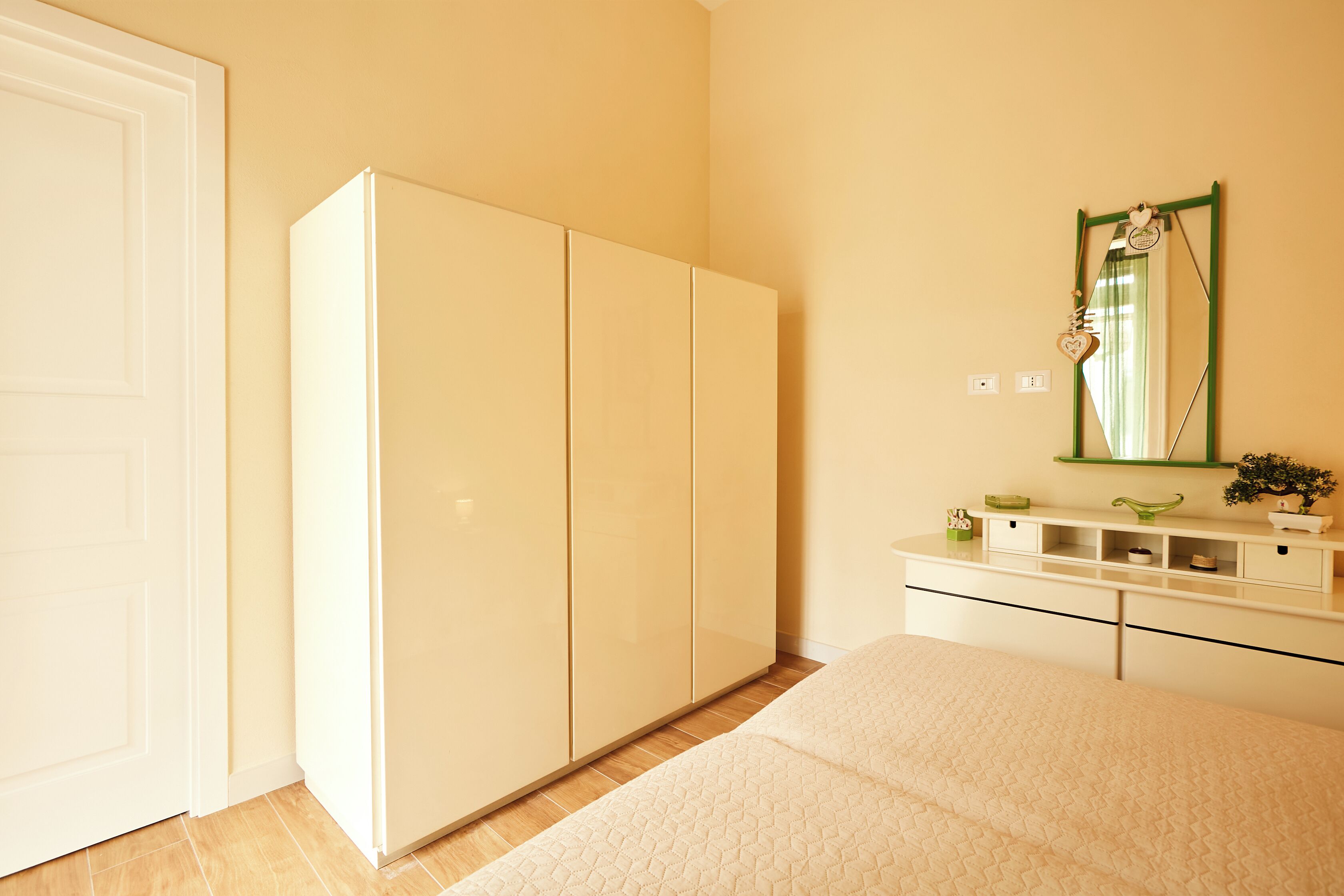 A bedroom with a bed, a wardrobe, a dresser, and a mirror.