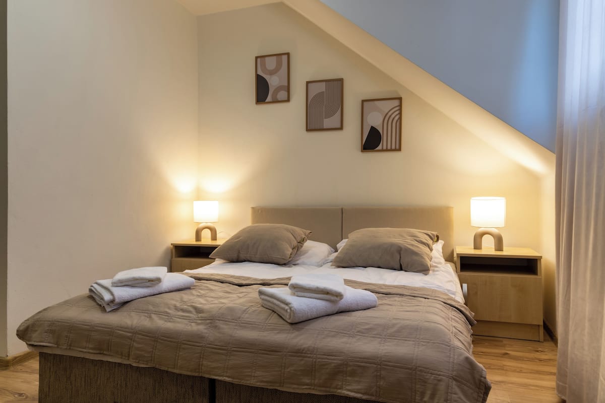Une chambre à coucher comprenant un lit, deux tables de chevet et trois lampes fixées au mur.