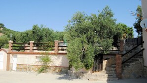 A courtyard with a brick wall, a metal gate, and a staircase leading to a building.