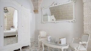 A room with a bed, a white wardrobe, a mirror, two chairs, a small table with a kettle and glasses, and patterned floor tiles. - Marchesa – Two-Bedroom Suite with Panoramic Terrace in the Historic Center (Monopoli)