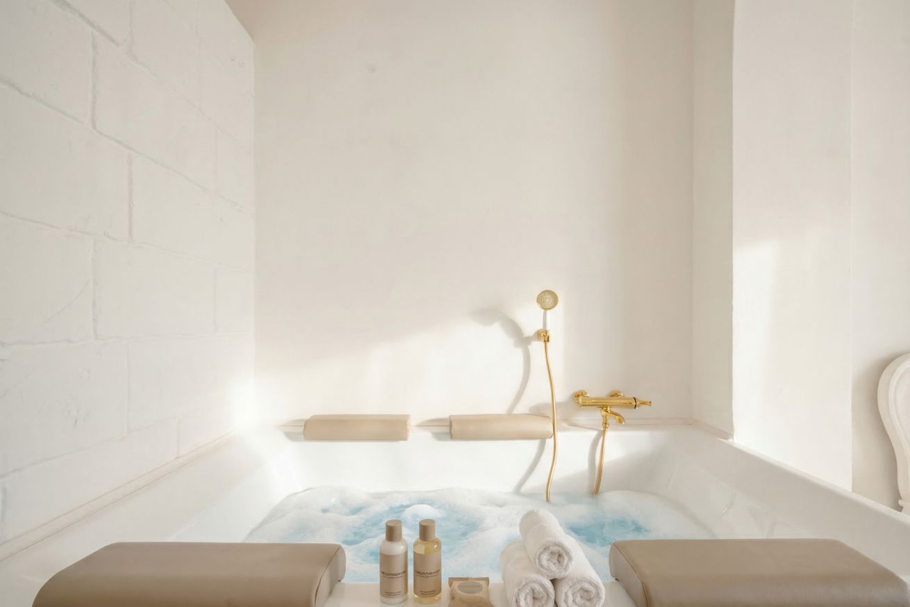 A bathroom with a bathtub, towels, and toiletries.