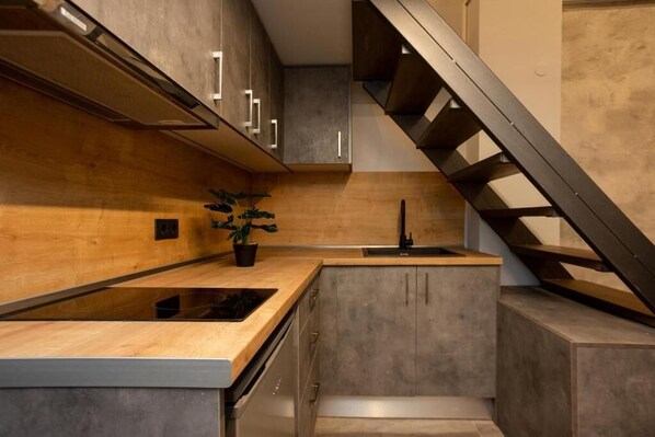 A modern kitchen with a wooden countertop, built-in cabinets, and a stainless steel range hood. - Dialeti Loft (Thessaloniki)