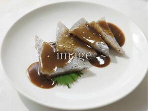 Une assiette blanche contenant un plat de poisson et une sauce.