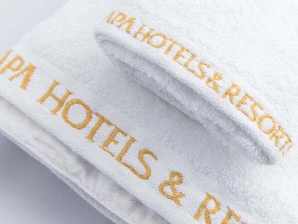Een witte handdoek met “IPA Hotels & Resort” in goud geborduurd.
