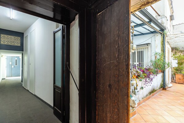Un couloir avec un cadre de porte en bois, un sol carrelé et un mur orné d’un motif décoratif.