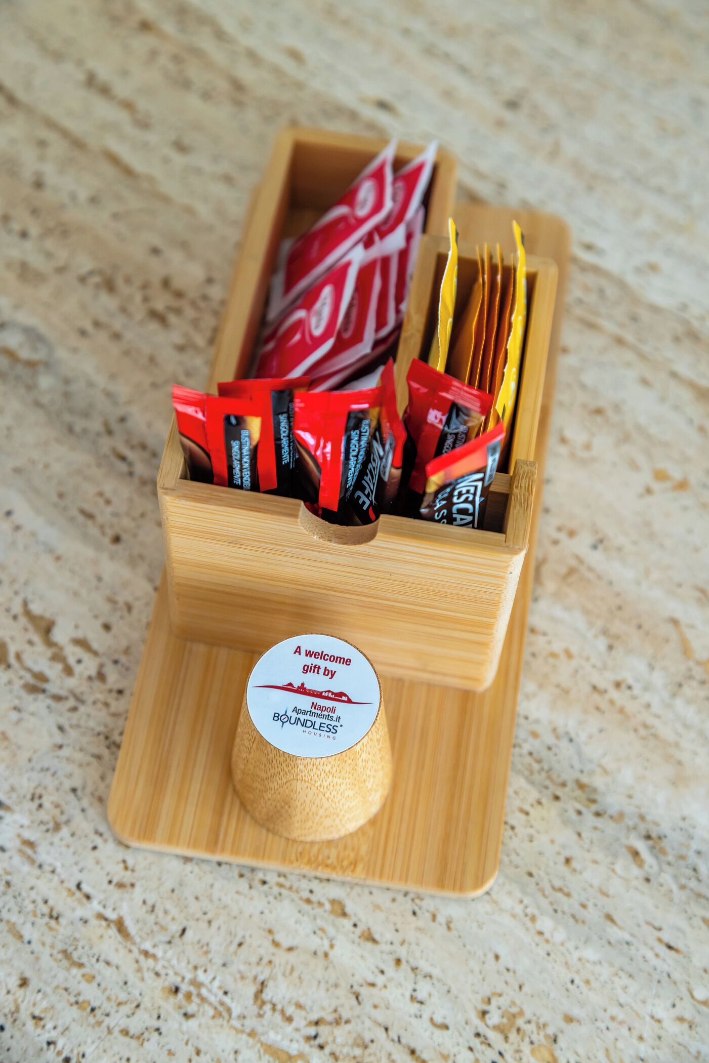 Ein Holztablett mit einem Etikett, das ein Willkommensgeschenk von Napoli Apartments.it anzeigt.