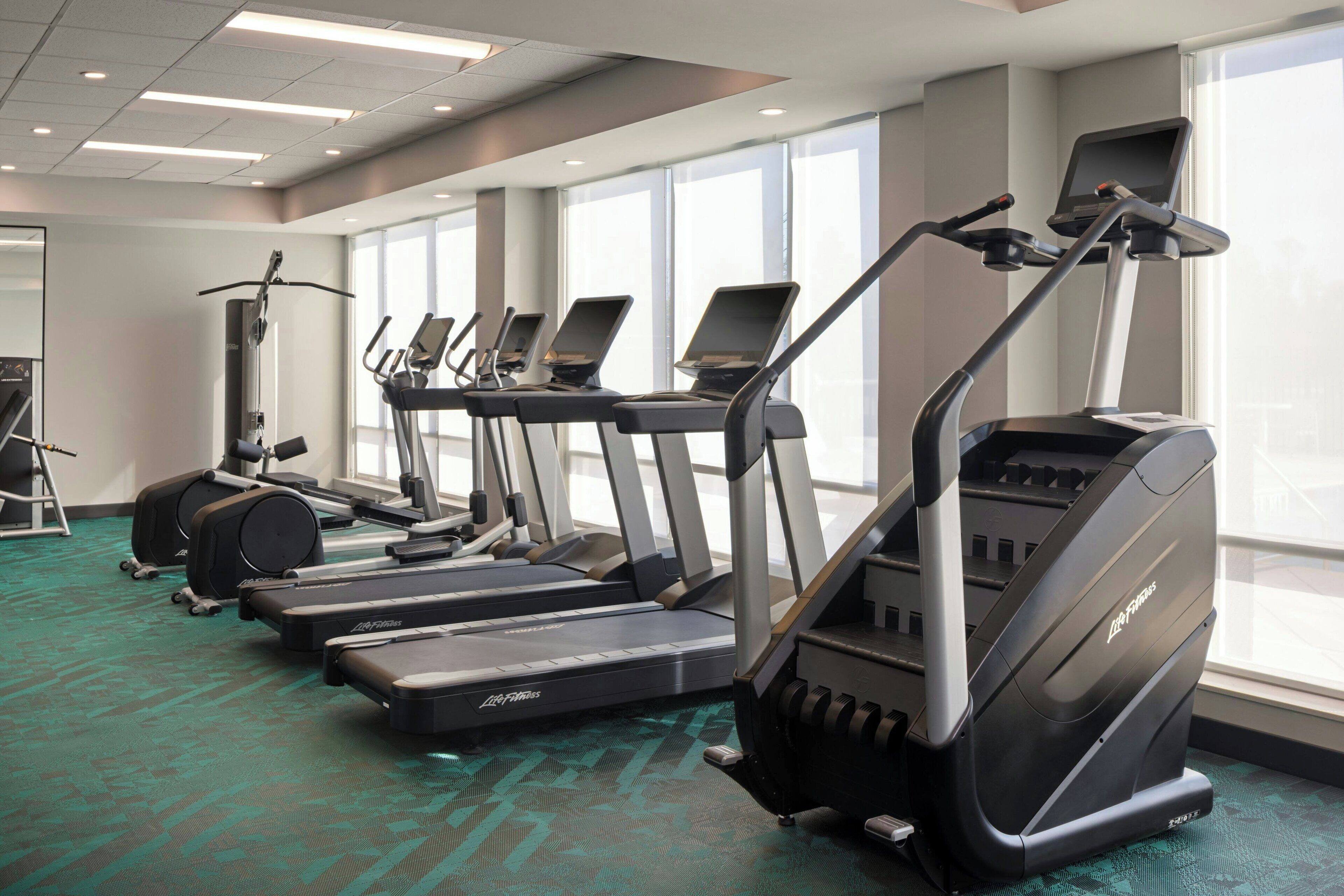 A gym with treadmills, ellipticals, and a stationary bike.