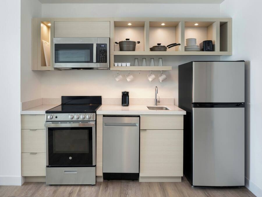 A compact kitchen with a built-in microwave, oven, dishwasher, and refrigerator.