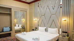 Een hotelkamer met een groot bed, een spiegel, nachtkastjes en een kamerbreed tapijt met dessin.