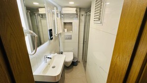 Een kleine badkamer met een wastafel, toilet en douche.