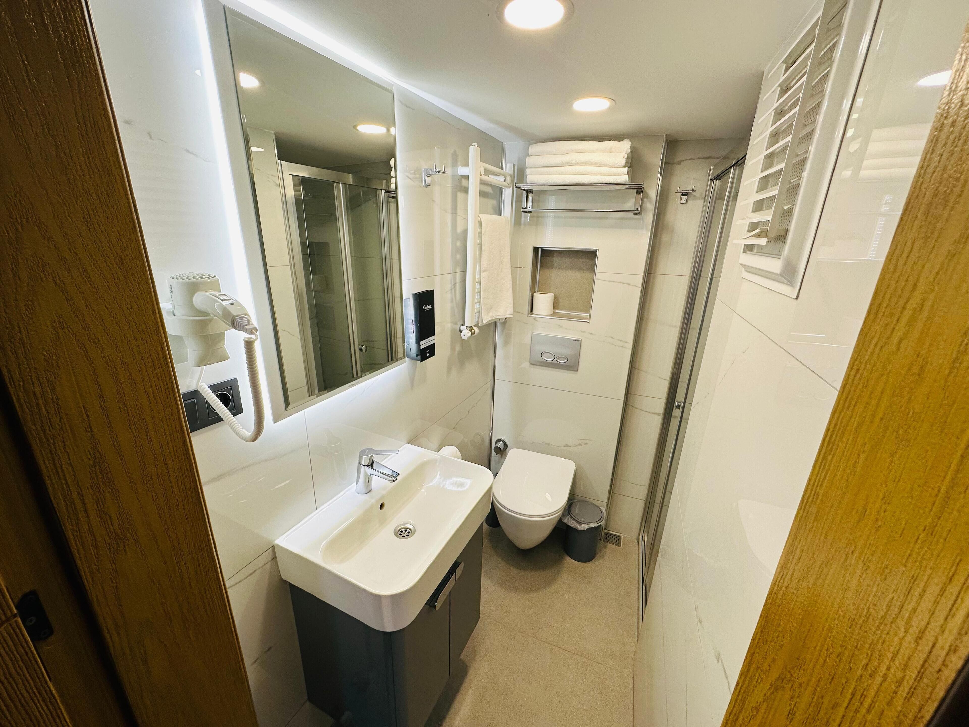 Un baño pequeño y funcional con lavamanos, inodoro y ducha.