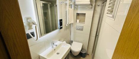 Un baño pequeño y funcional con lavamanos, inodoro y ducha.