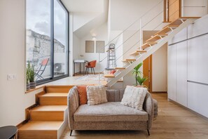 A modern interior with a staircase, a sofa, and a dining area. - Saldanha Boho Duplex (Porto)