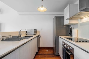 A compact kitchen with a microwave, toaster, refrigerator, and stove.