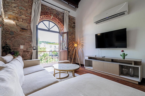 A modern living room with a stone wall, a large window, a flat-screen TV, and a cozy seating area.
