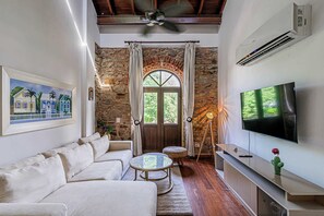 A living room with a stone wall, a sofa, a TV, and a ceiling fan. - w* | Classy 1BR in Plaza Herrera w/ Balcony (Panamá)
