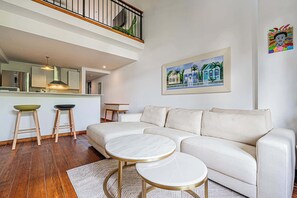 A modern living room with a white sofa, two round coffee tables, and a kitchen in the background. - w* | Classy 1BR in Plaza Herrera w/ Balcony (Panamá)