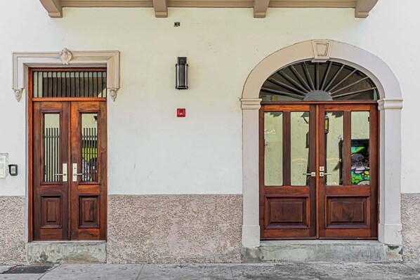 A building with two wooden doors, one with a barred window and the other with an arched entrance. - w* | Classy 1BR in Plaza Herrera w/ Balcony (Panamá)