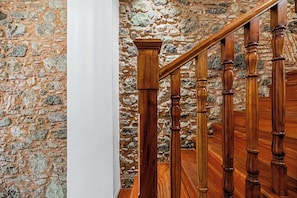 A wooden staircase with a stone wall background.
