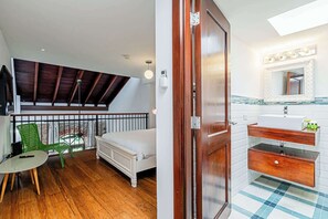 A bedroom with a bed, a green chair, a balcony with a wooden railing, and a bathroom with a sink and mirror. - w* | Classy 1BR in Plaza Herrera w/ Balcony (Panamá)