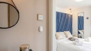 Une chambre d’hôtel avec un lit, un miroir rond, une table de chevet avec une bougie et un téléphone fixé au mur.