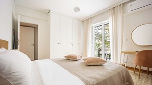 A bedroom with a bed, a desk, a chair, and a view of the outdoors. - Attica Skyline Living (Athens)