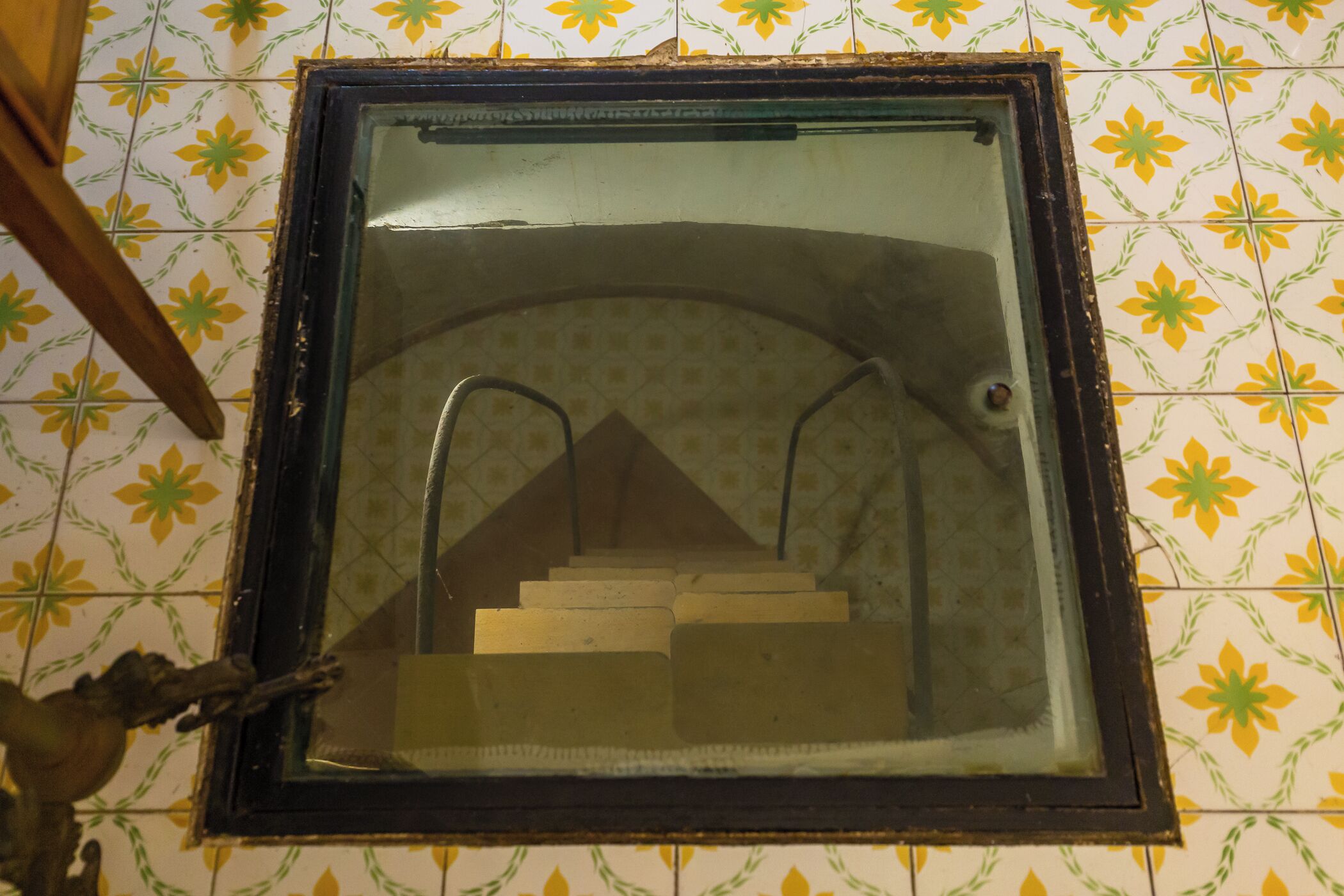Een raam met metalen frame en uitzicht op een trap.