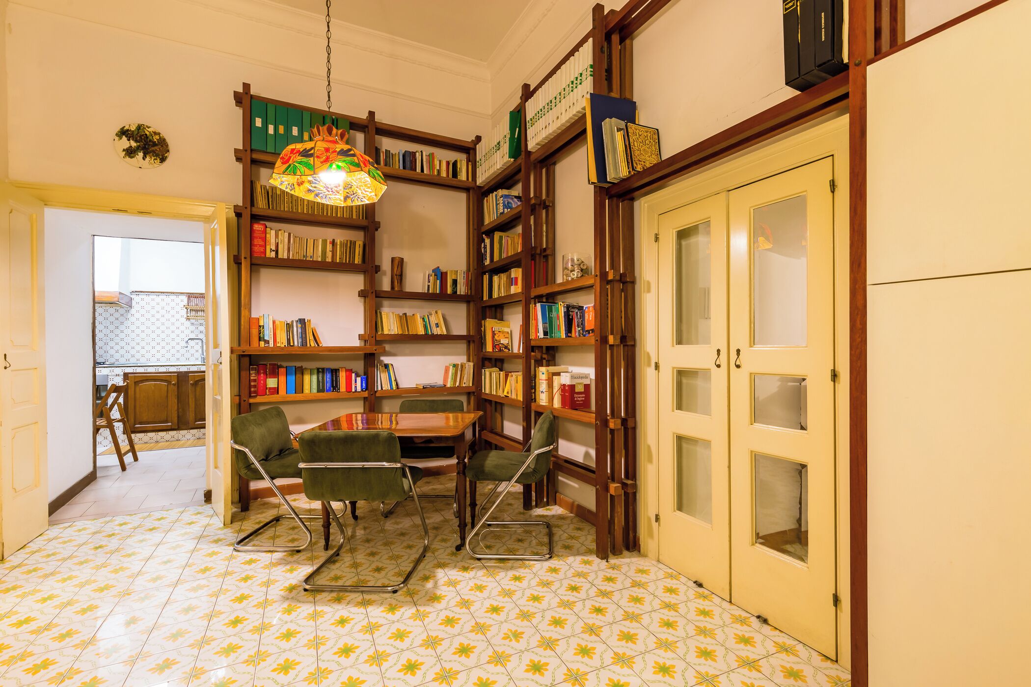 A library with bookshelves, a table with chairs, and a patterned floor.