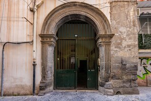 An arched entrance with a metal gate, a stone wall, and a door with a small window above it. - Terrazza San Paolo by Napoliapartments (Naples)