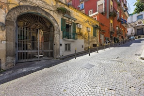 A cobblestone street with historic buildings, a metal gate, and a clear sky. - Terrazza Spaccanapoli by Napoliapartments (Naples)