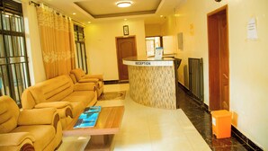 A reception area with a reception desk, a sofa set, and a wooden coffee table. - Novaland Hotel Rw (Kigali)