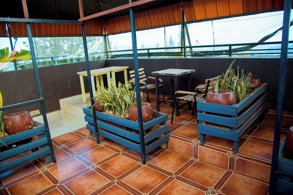 An outdoor patio with wooden furniture, terracotta tiles, and potted plants.