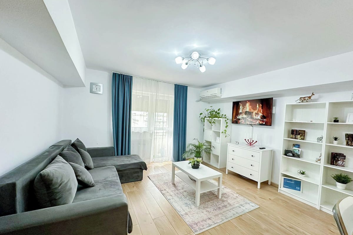 Ein modernes Wohnzimmer mit einem grauen Sofa, einem weißen Couchtisch und einem Bücherregal.