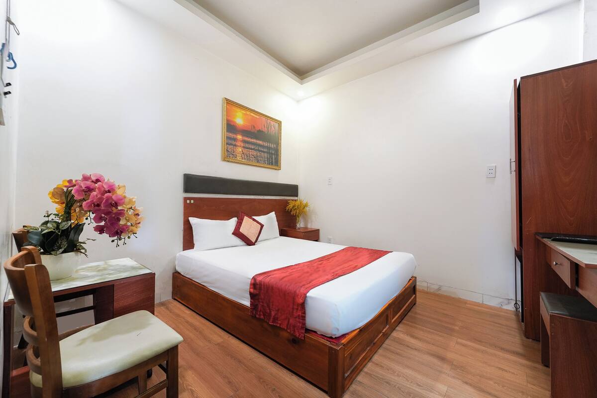 A neatly arranged bedroom with a wooden bed, a desk, and a chair.