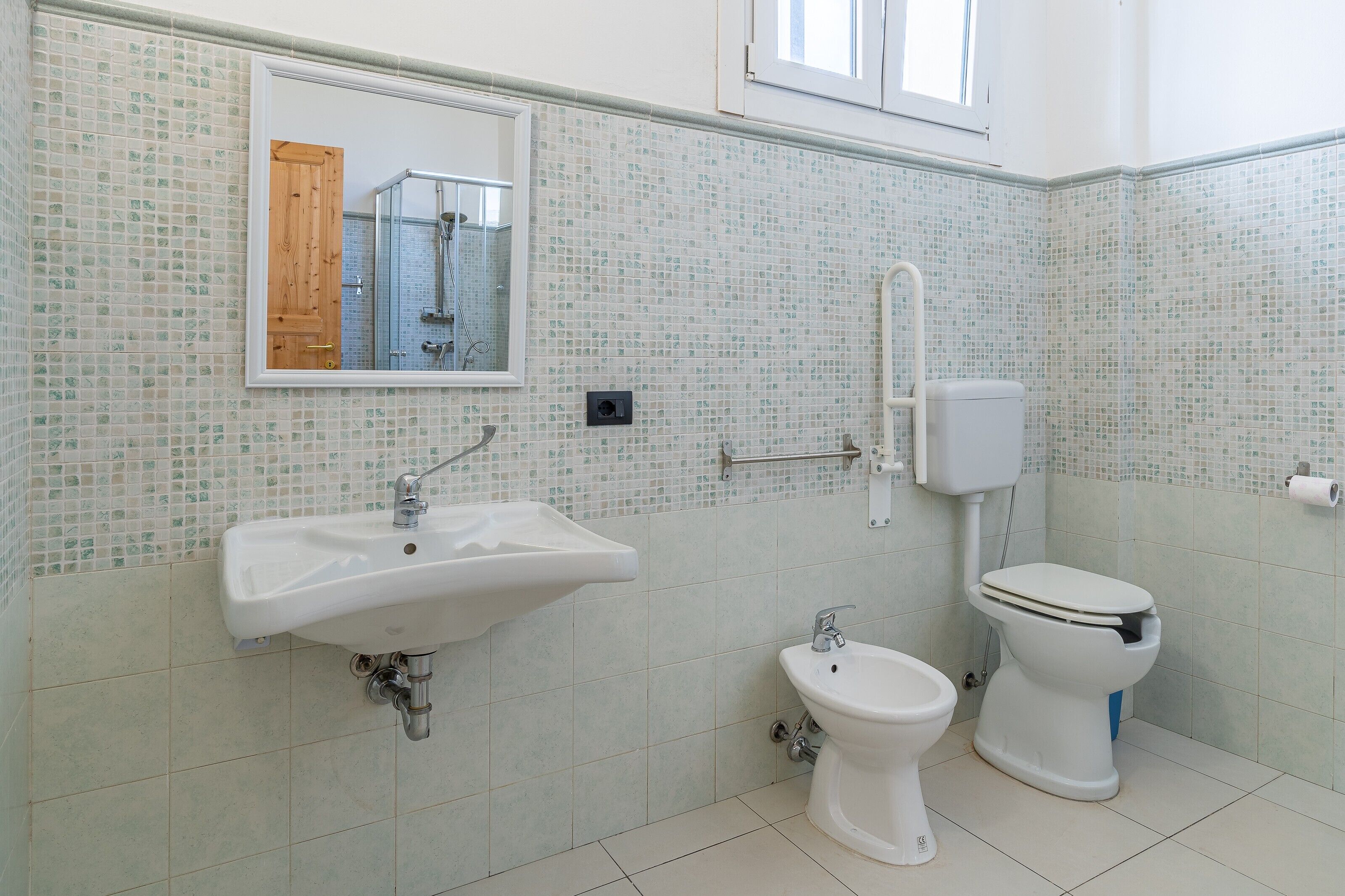 A bathroom with a sink, bidet, toilet, and a mirror.