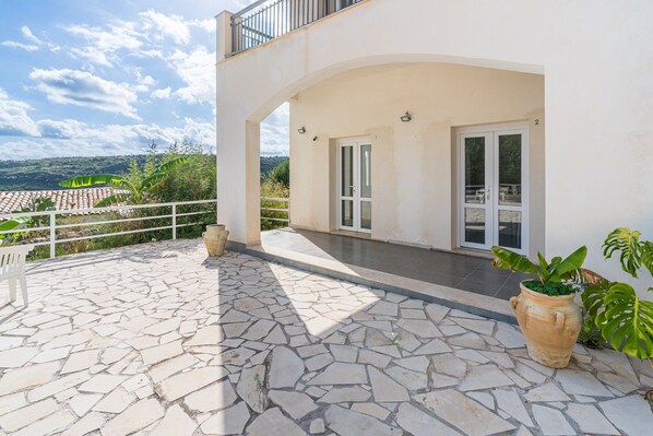 Un bâtiment moderne doté d’une terrasse en pierre, d’un balcon et offrant une vue sur le paysage.