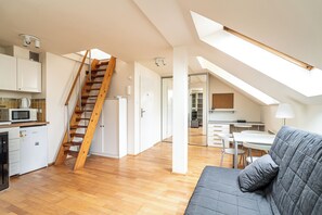 A spacious loft with a kitchen, dining area, and a staircase leading to an upper level. - RentPlanet - Apartament Garbarska (Kraków)