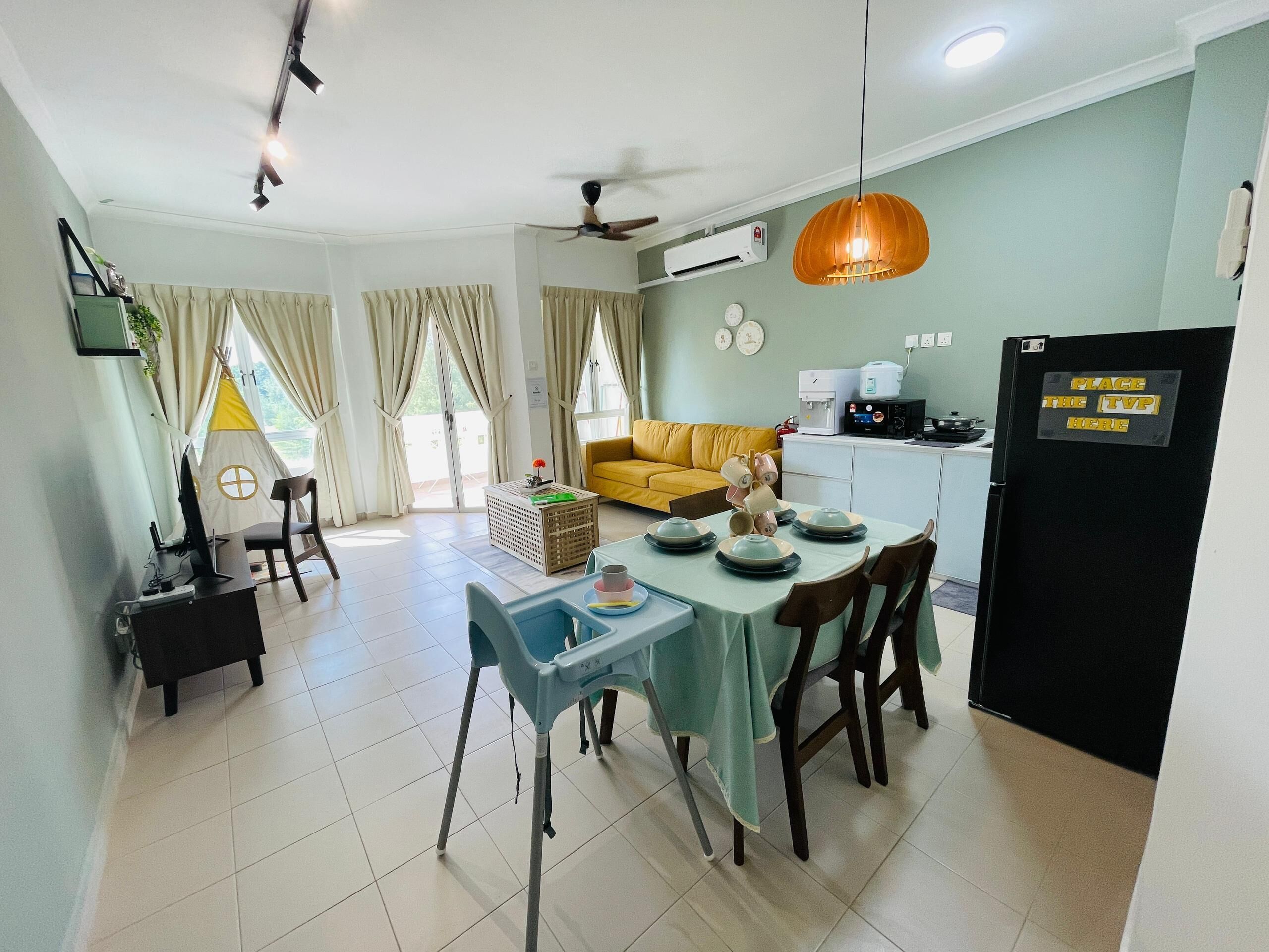 Una cocina moderna con comedor, un sofá amarillo y una mesa preparada para cuatro personas.