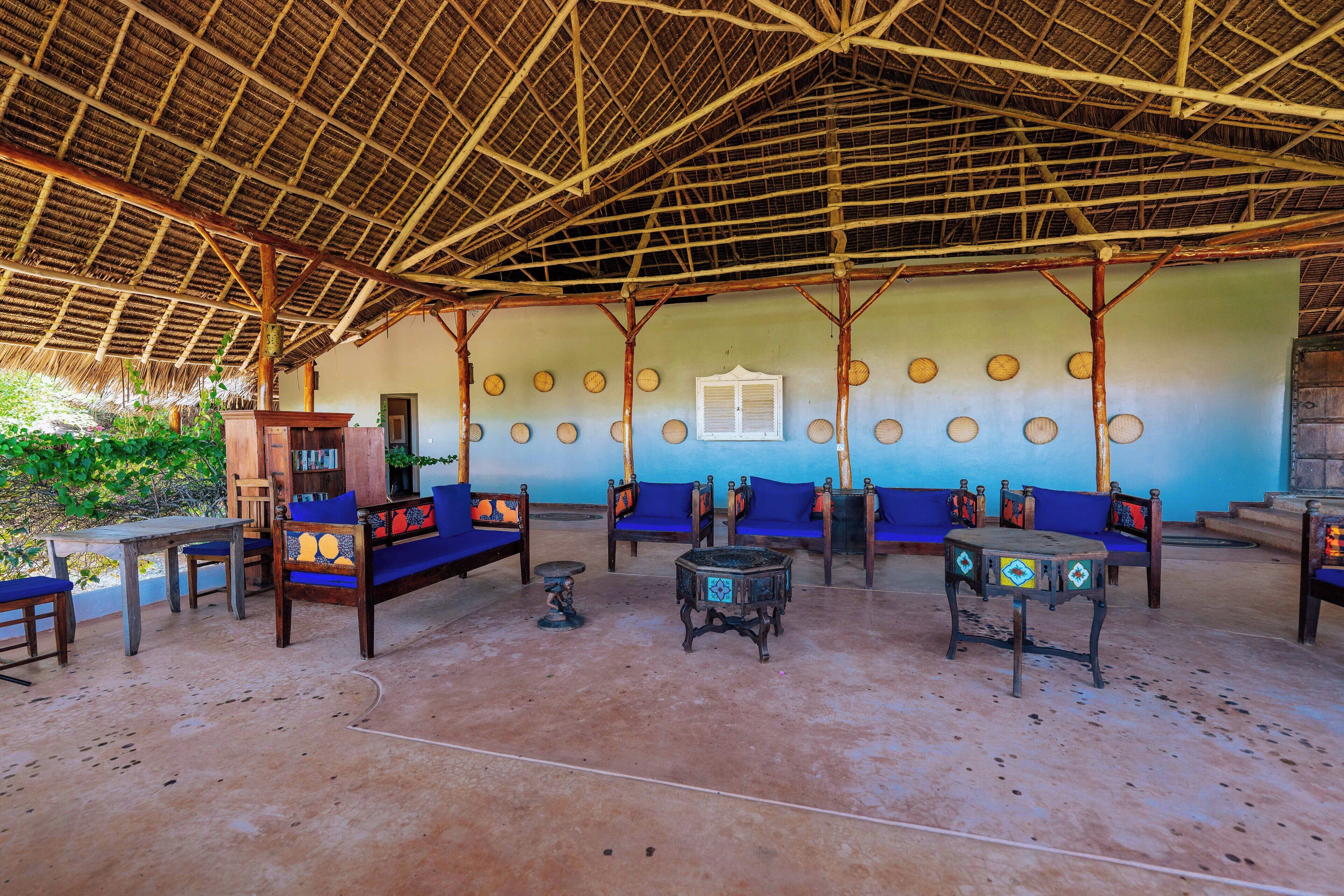 An open-air lounge with wooden furniture and a thatched roof.