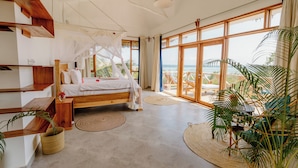 Un dormitorio amplio con una cama grande, muebles de madera y vista al océano.