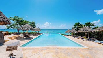 Una piscina al aire libre, sombrillas, sillones reclinables de piscina
