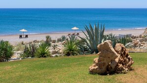 A beach with two sun loungers and umbrellas, surrounded by cacti and rocks. - White Village (Rhodes)
