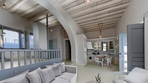 A spacious living area with a large sofa, a dining table, and a kitchen in the background. - White Village (Rhodes)