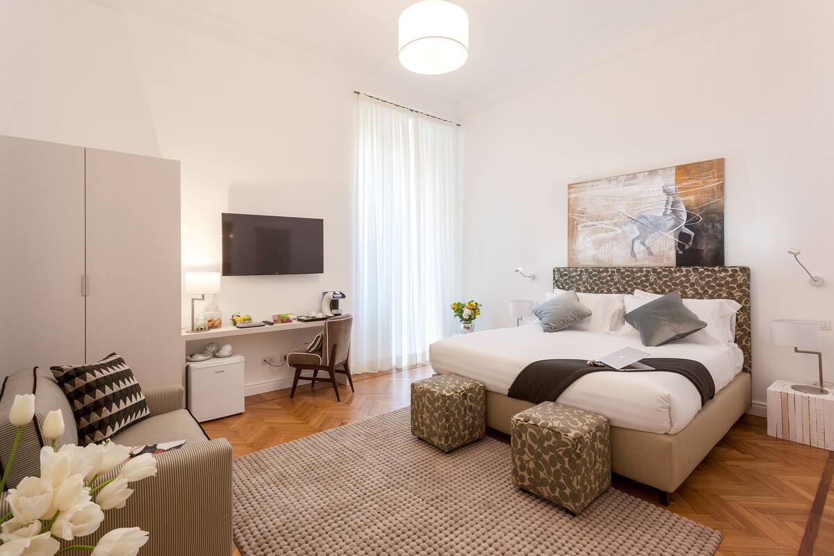 A modern bedroom with a bed, a desk, a chair, and a TV.